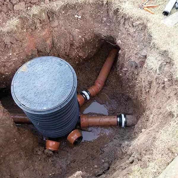 Excavation with a new drain chamber being built during a drain repair