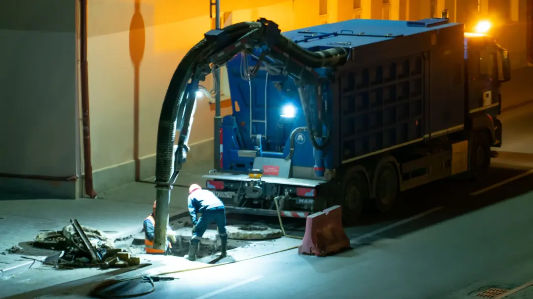 Emergency drainage crew working at an open manhole at night