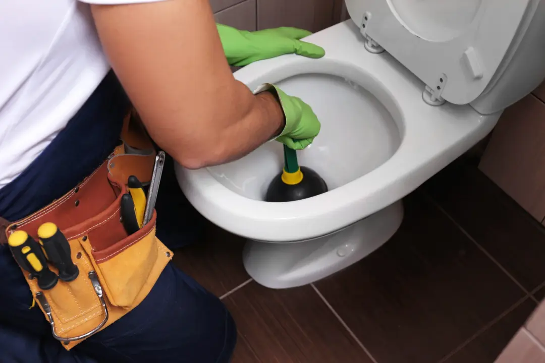 Plumber unblocking a toilet with a plunger